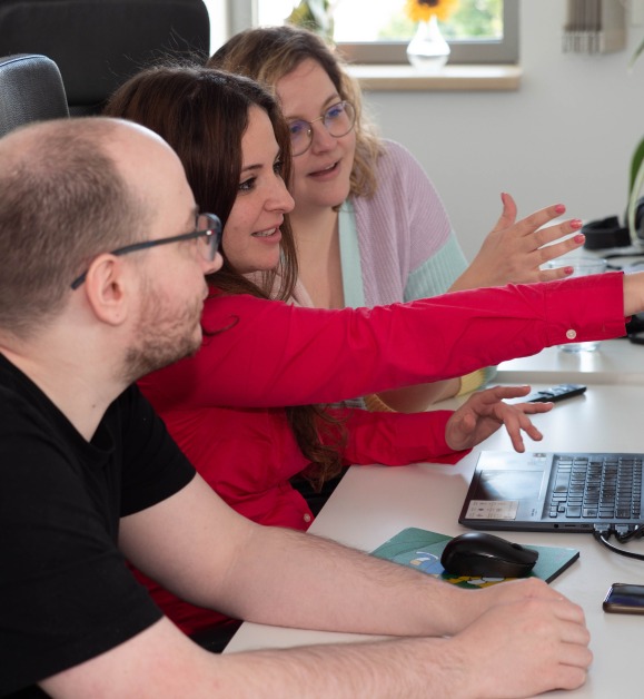 Three coworkers sitting around a table in the office, actively discussing ideas.
